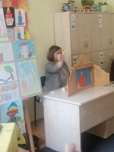 Nauczycielka z wyciągniętym kciukiem z pacynką prezentuje teatr karty narracyjne kamishibai 