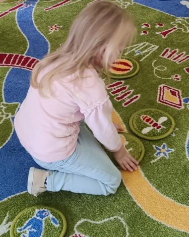 Na zdjęciu bawiące się dziecko. Widać dywan edukacyjny.